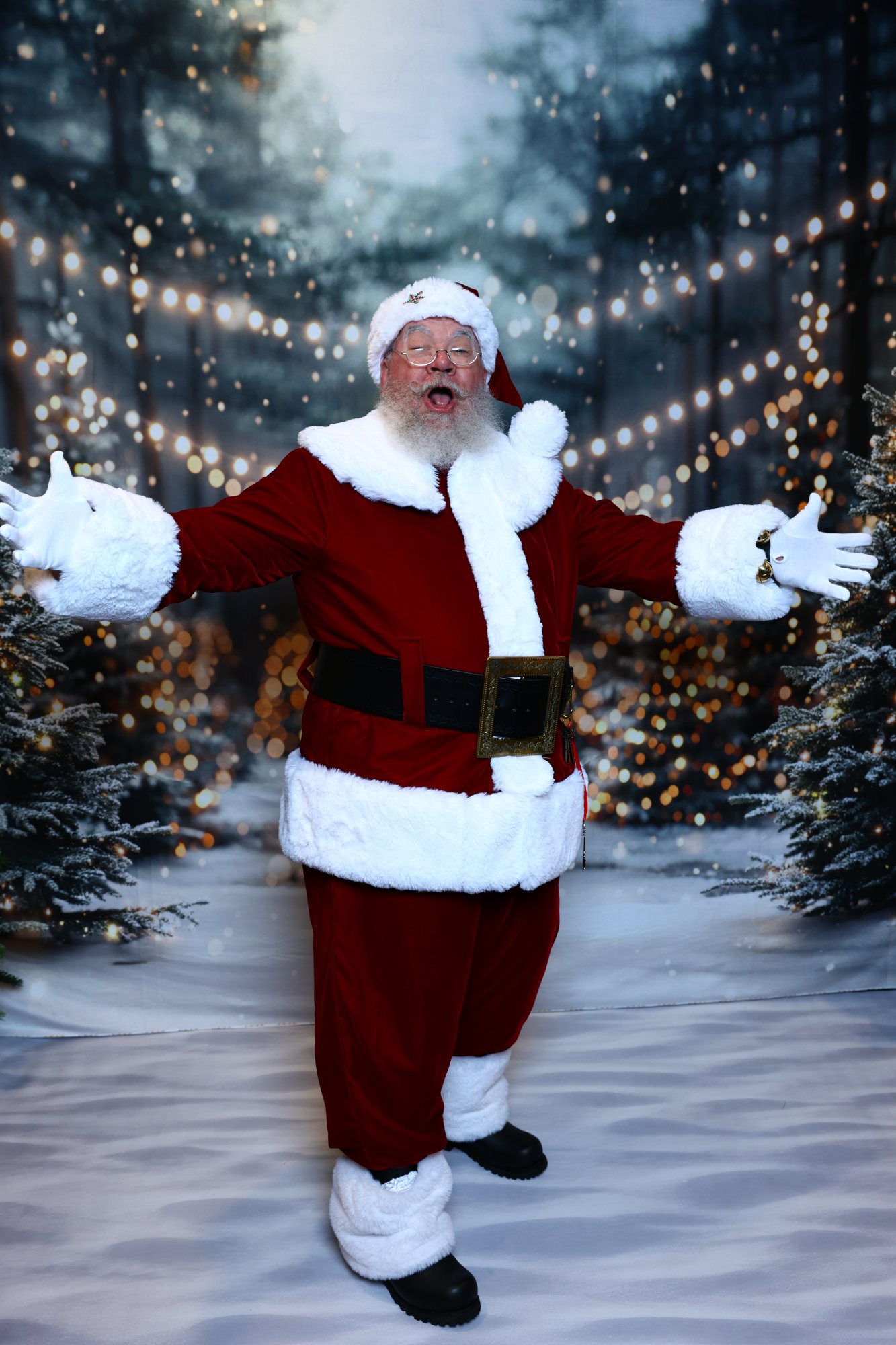 Santa Strickland with his arms flung wide in welcome among snowy pines