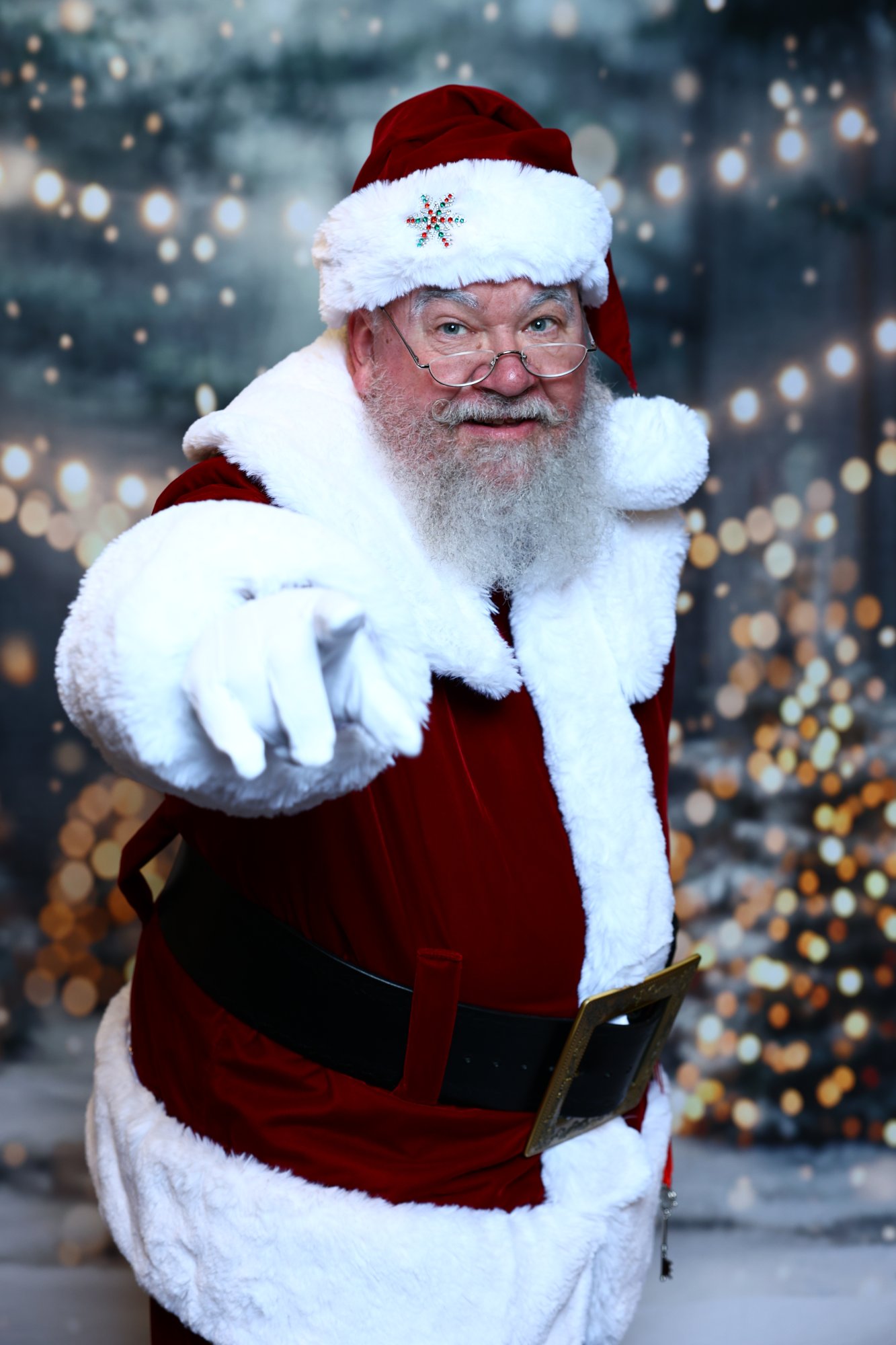 Santa Strickland pointing toward the camera against a backdrop of winter lights
