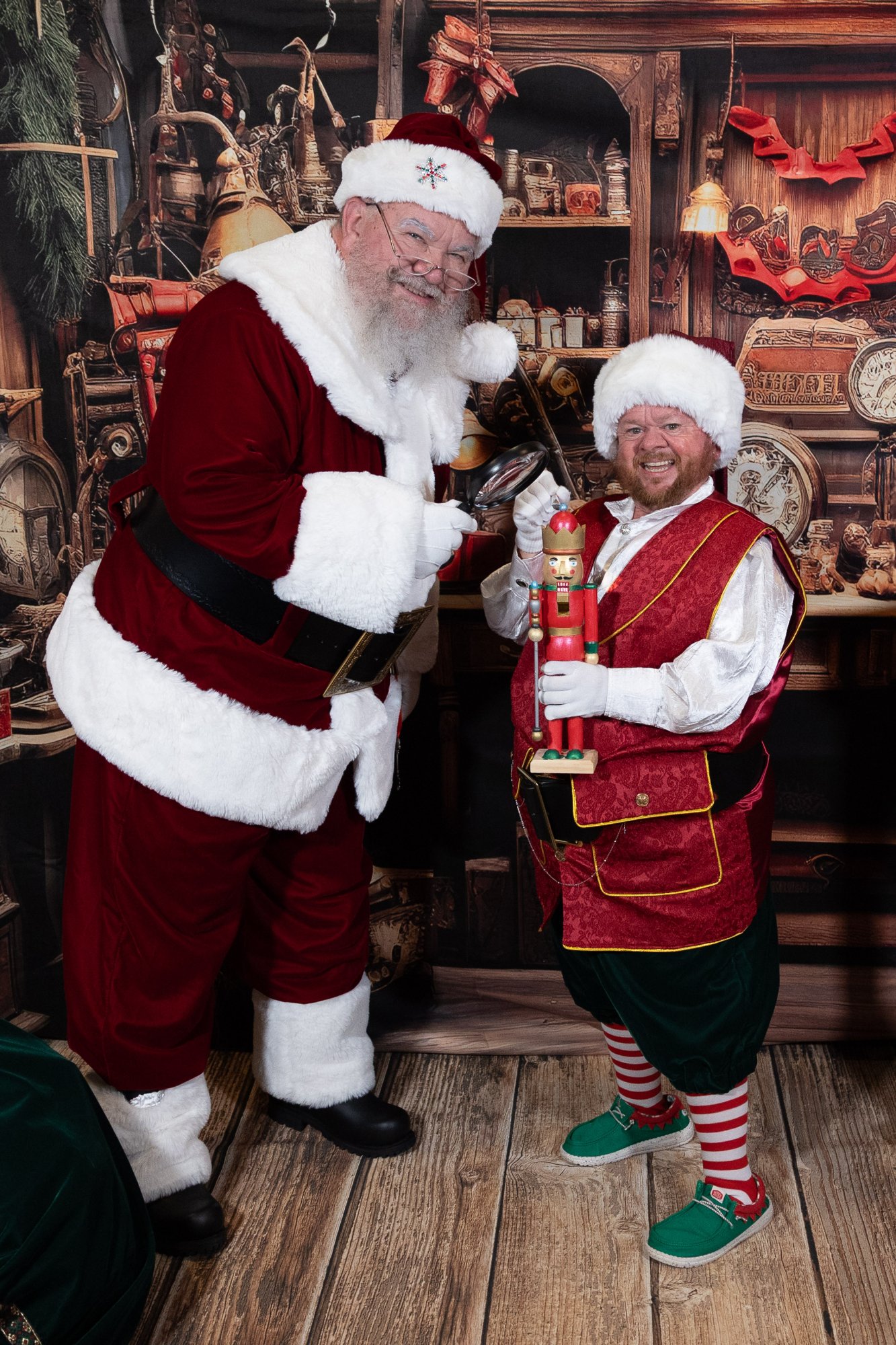Santa Strickland and his elf in the workshop, the elf holding a wooden nutcracker