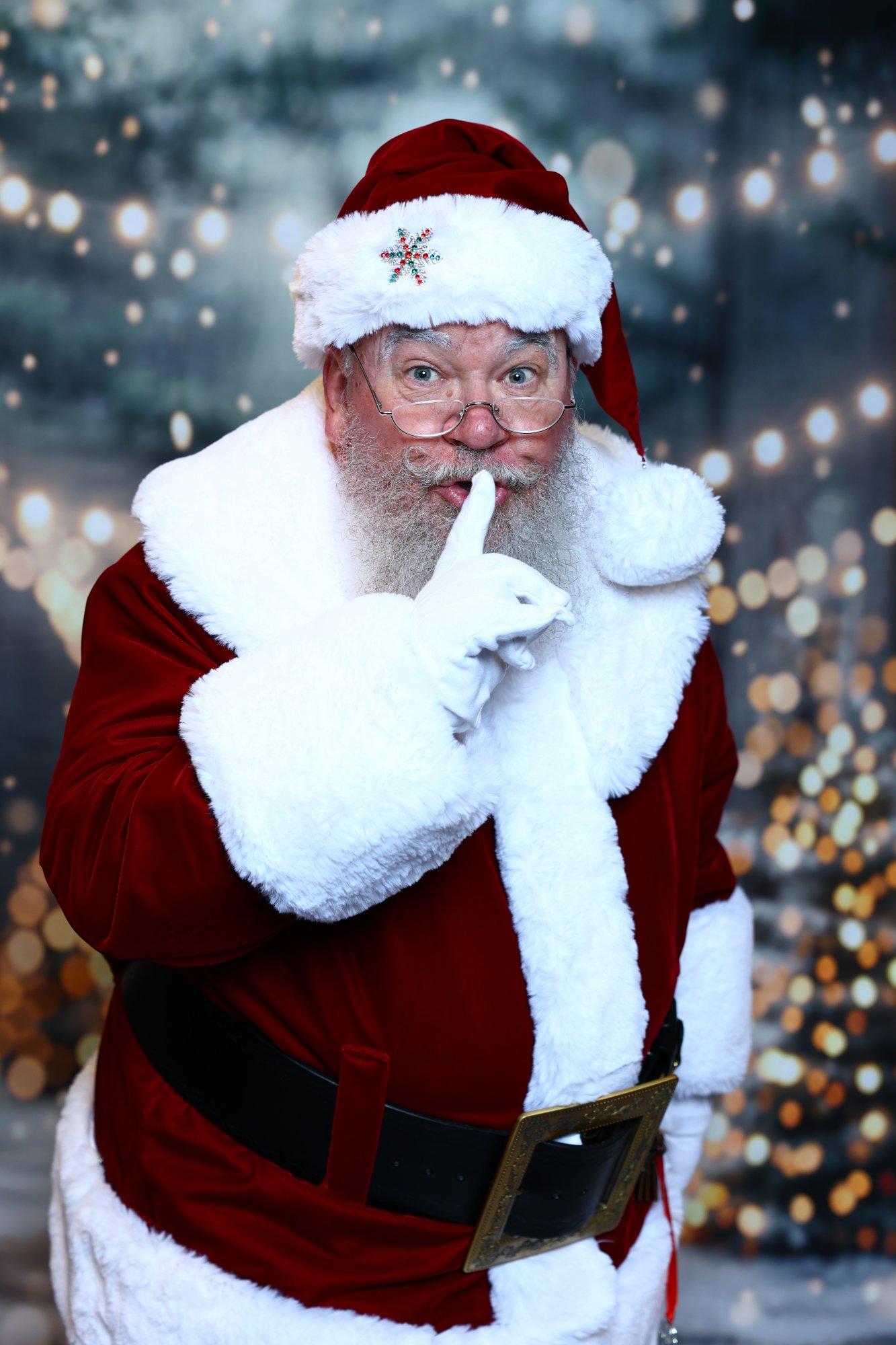 Santa Strickland with a gloved finger to his lips, hushing a Christmas secret