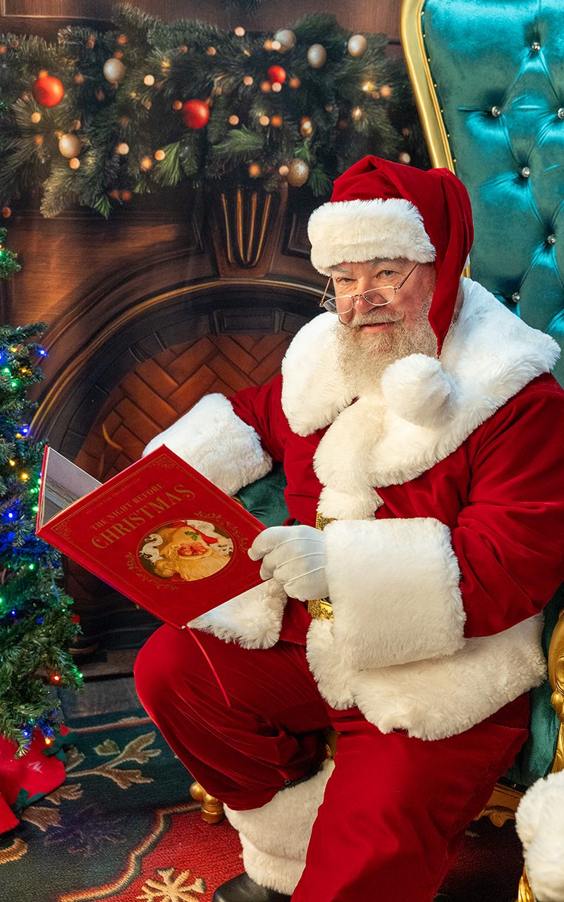Santa Strickland reading 'The Night Before Christmas' beside the fireplace