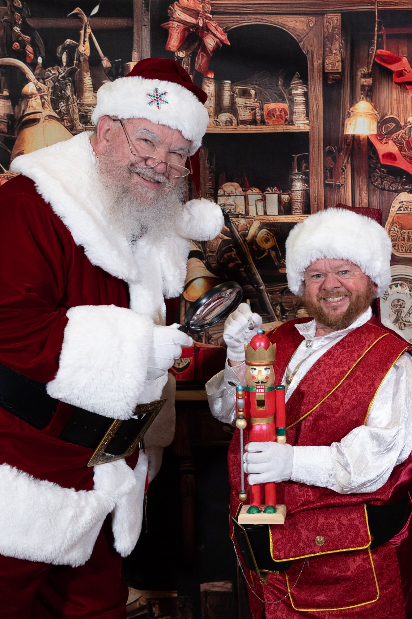 Santa Strickland and his elf sharing a laugh among the shelves of the toy workshop